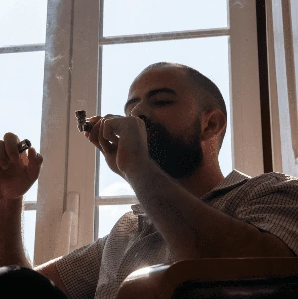 Man smoking and relaxing by a window.