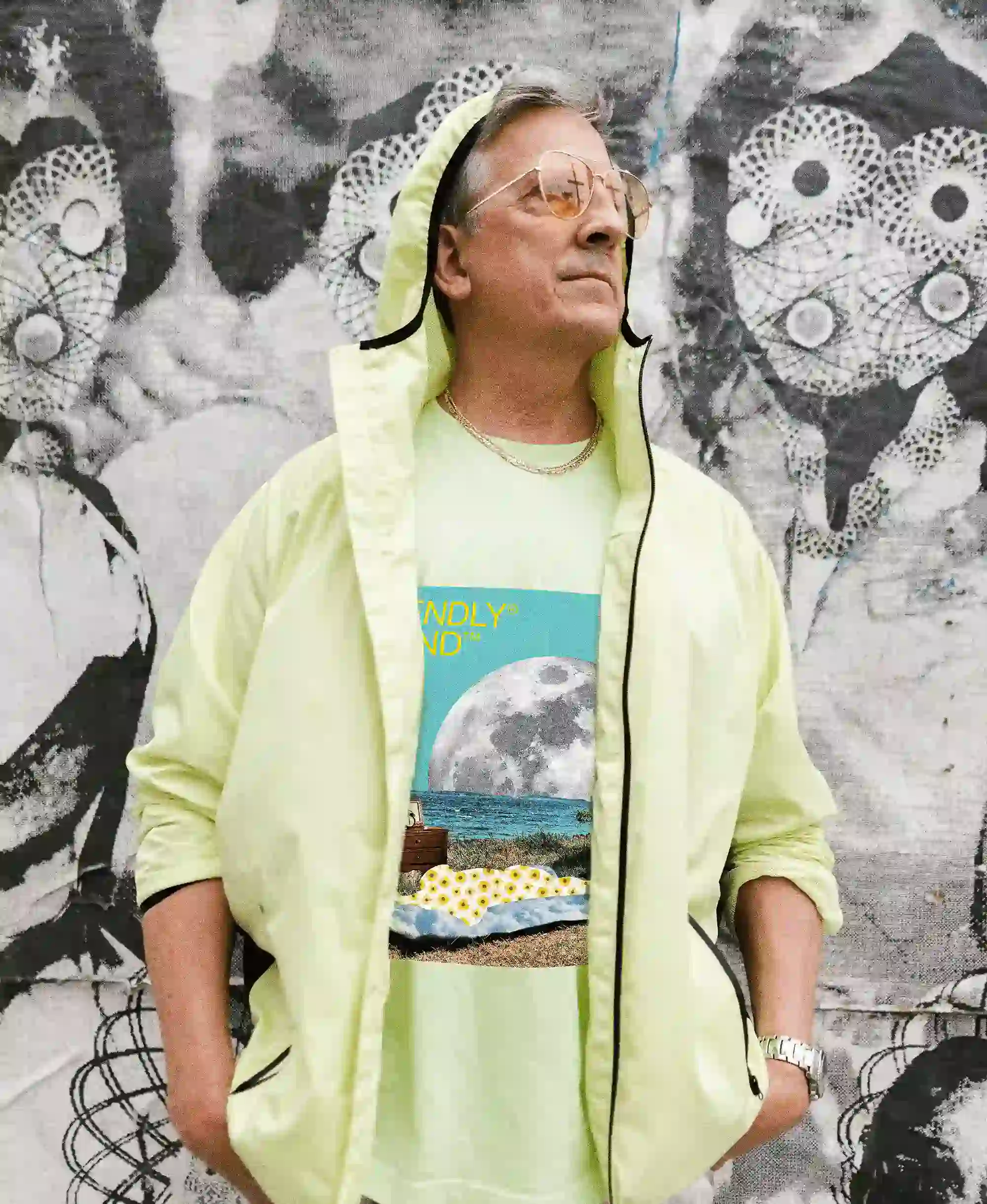 Older man standing in front of a wall of graffiti wearing a T-shirt of Friendly Gear.